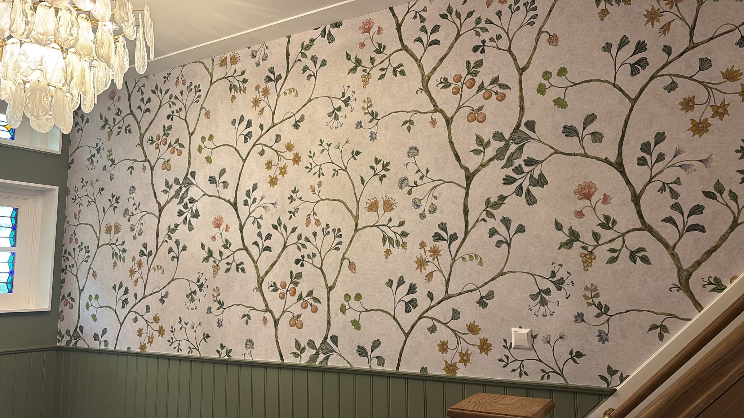 Traditioneel behang met bloemmotief in een hal, aangebracht boven groene lambrisering door Mourits Schilderwerken